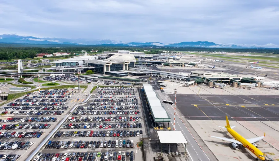 Aerial view of an airport terminal with aircraft at the gates and a car park in front