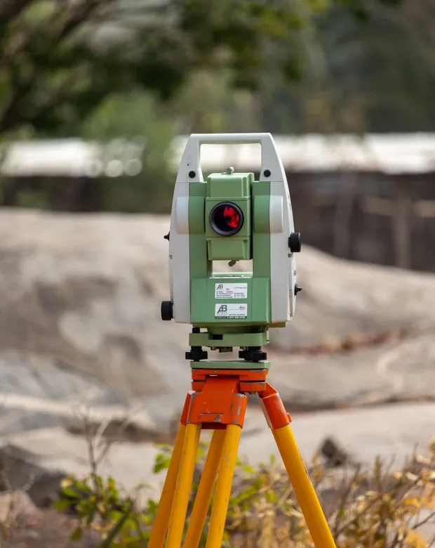 A surveying instrument mounted on a tripod on bare ground