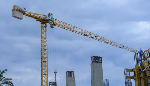 A tower crane standing over the concrete frame of a building under construction