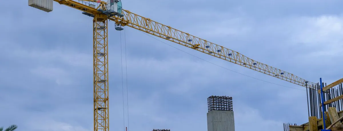A tower crane standing over the concrete frame of a building under construction
