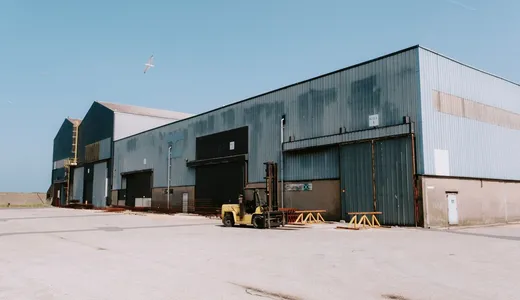 A long single-storey industrial shed with a forklift parked outside
