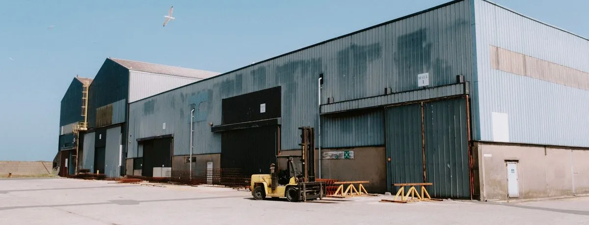 A long single-storey industrial shed with a forklift parked outside
